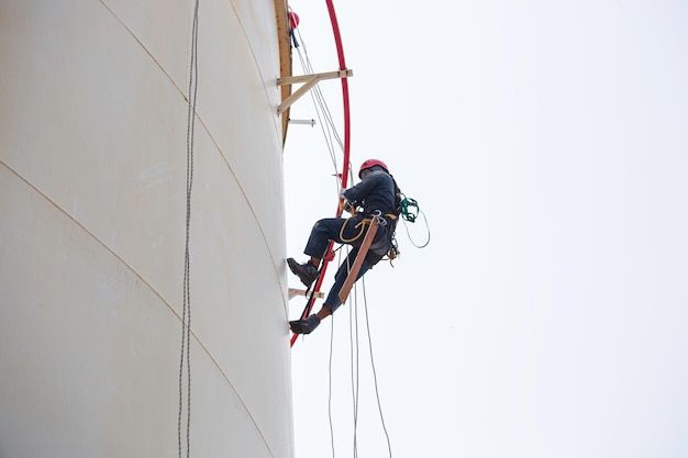trabalhador masculino acesso por corda industrial trabalhando em tanque de altura usando arnês capacete equipamento de segurança inspeção de acesso por corda do tanque de espessura foto premium